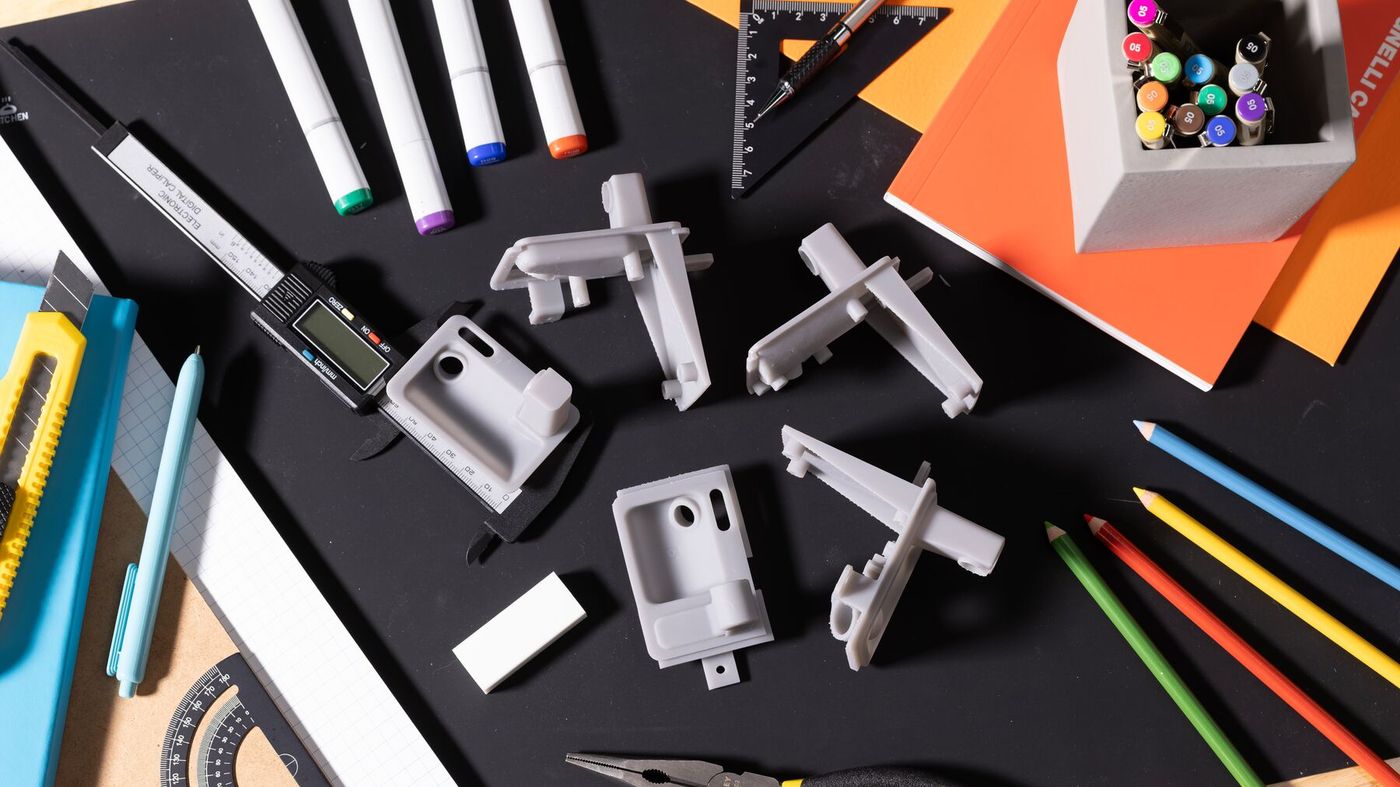 Grey printed brackets next to calipers and drafting tools
