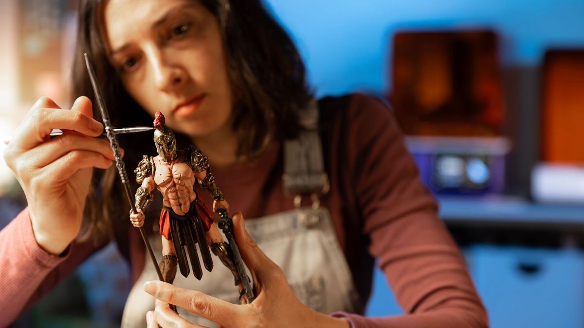 A painter detailing a printed miniature in a home studio