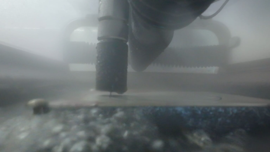 Laser cutter nozzle cutting a sheet inside a smoky enclosure