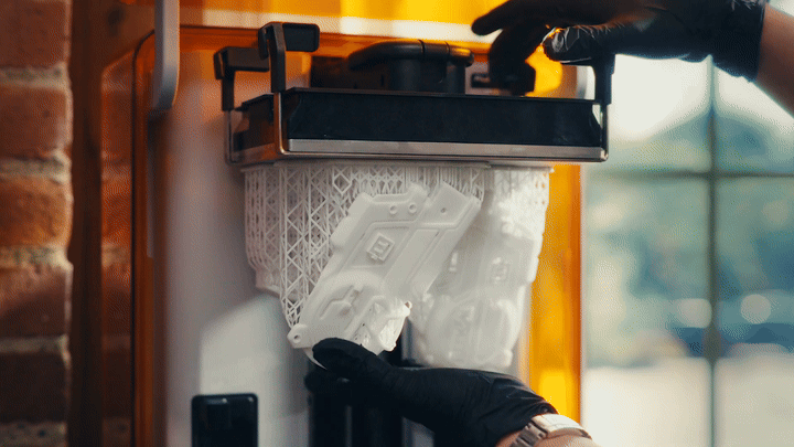 Gloved hands flexing Build Platform Flex so a white lattice print pops free