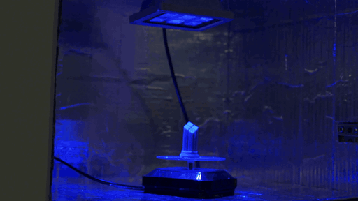 A small resin part turns under a separate UV curing lamp