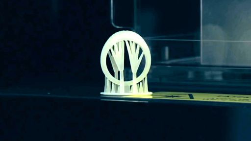A small resin ring test print with thin supports on a printer build plate